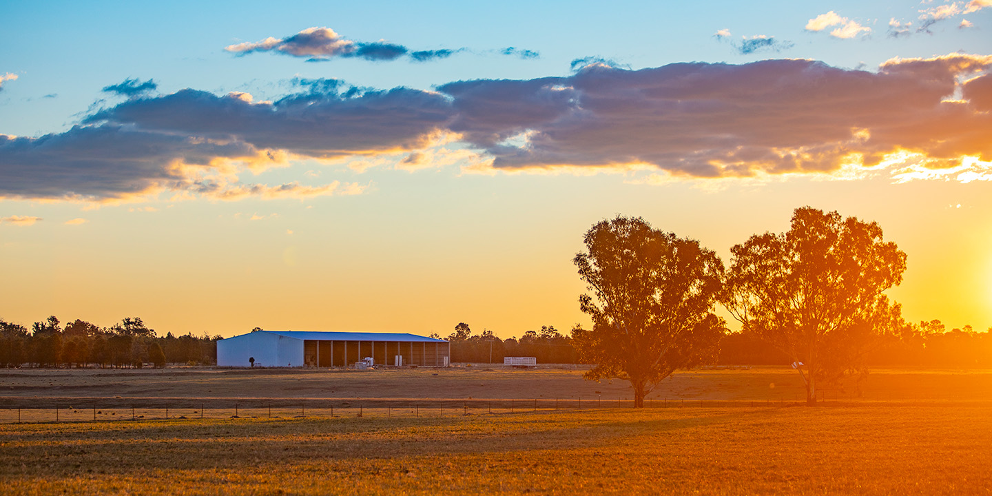Sunset over a field with a barn